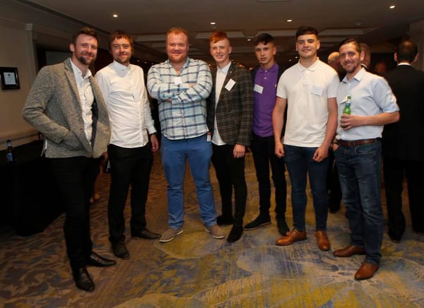 7 men ranging in ages stand proud at an awards ceremony