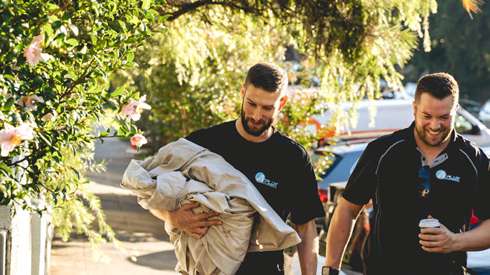 two men walking with gardening canvas in hand