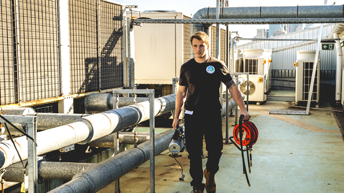 man walking carrying ventilation equipment in both hands 