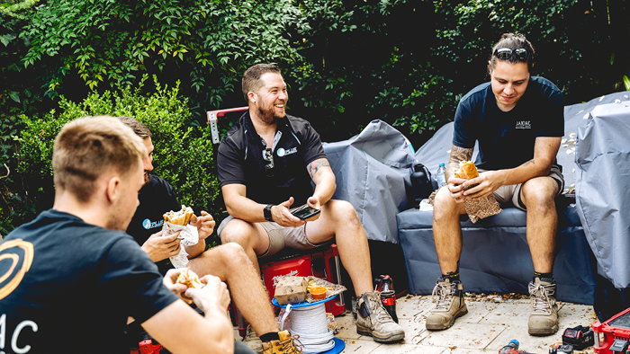 group of tradies sitting together outside having lunch