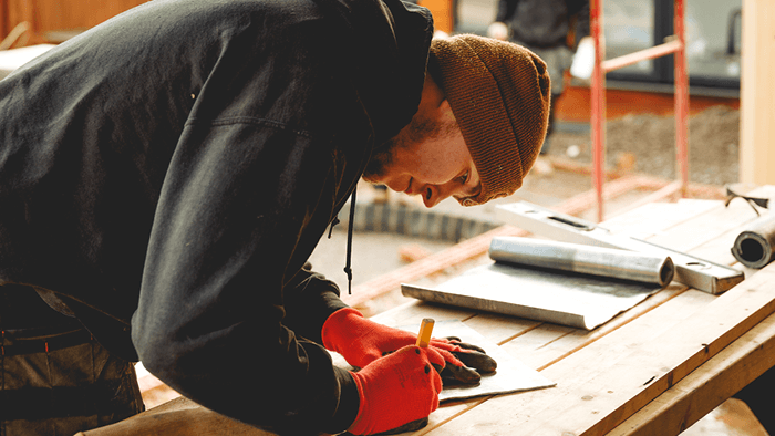 tradie bent over workbench marking timber 