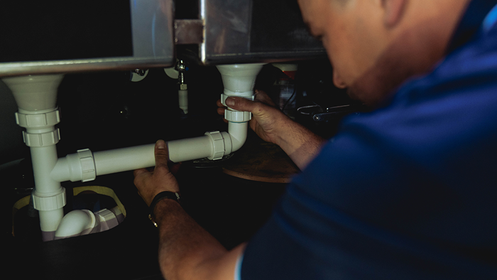 close up of plumber installing pipes under sink