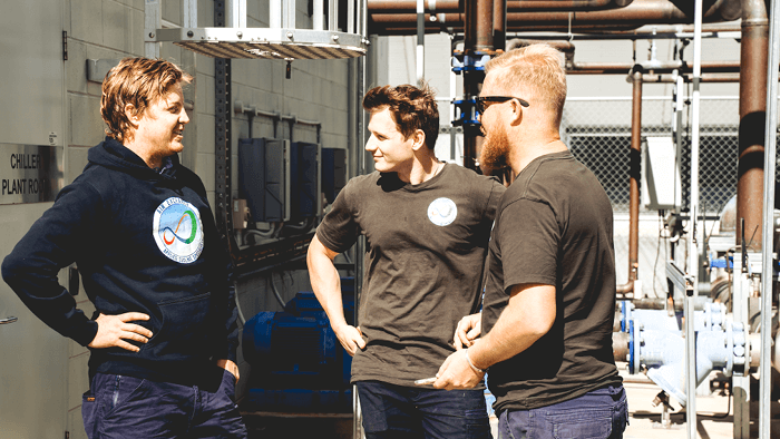 three hvac tradies standing outside surrounded by piping units 