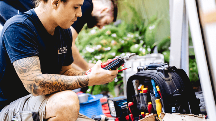 tradesperson on knees looking at phone and surrounded by tools