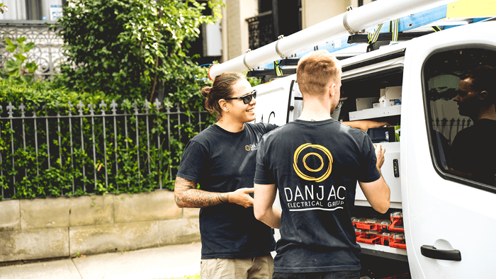 two tradespeople standing by the side door of electric company van