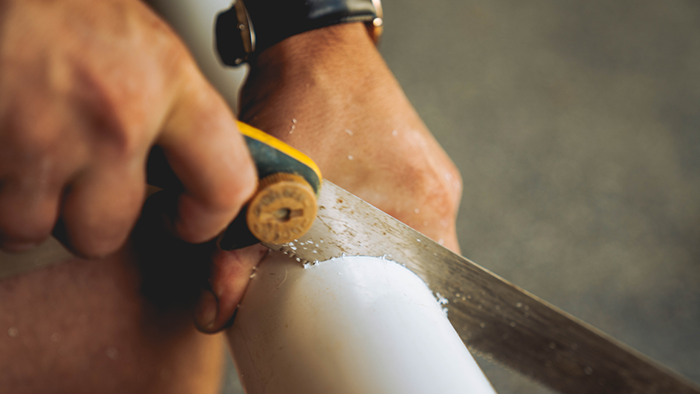 close up of hand cutting through plumping pipe