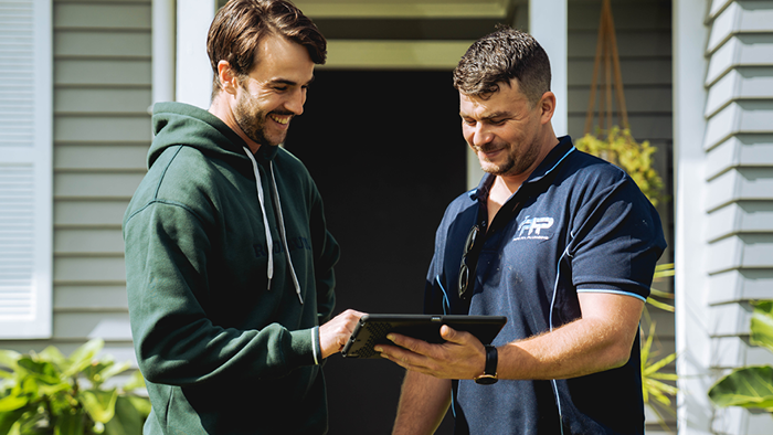 business owner looking at device with customer and smiling