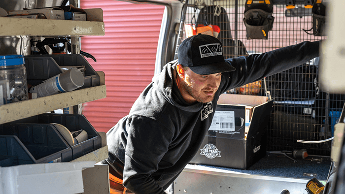 tradie looking inside work van surrounded by tools 