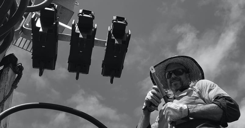 A low angle black and white photo of an electrician at work installing cable