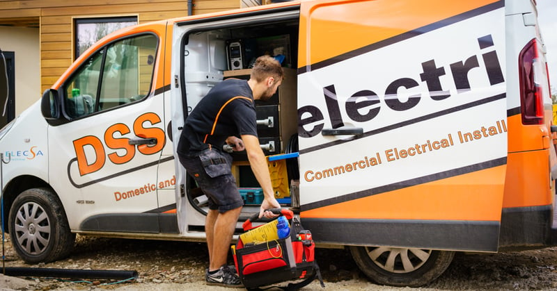 A photo of an electrician loading tools into a van