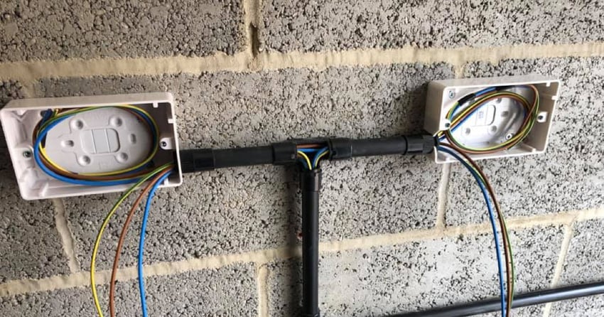 An installation of wiring for outdoors, attached to a grey brick wall
