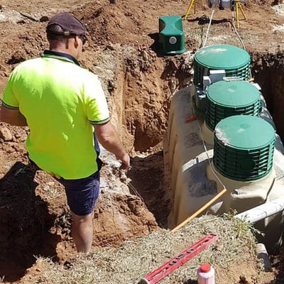 Toby supervises work dropping a tank into a dirt pit