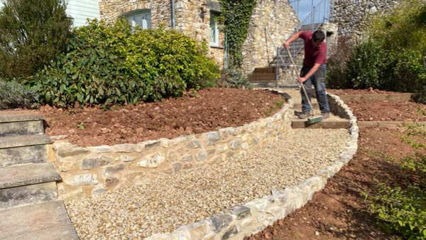 CaseStudy_jake_smith_construction_worker sweeping steps on rock path in a garden