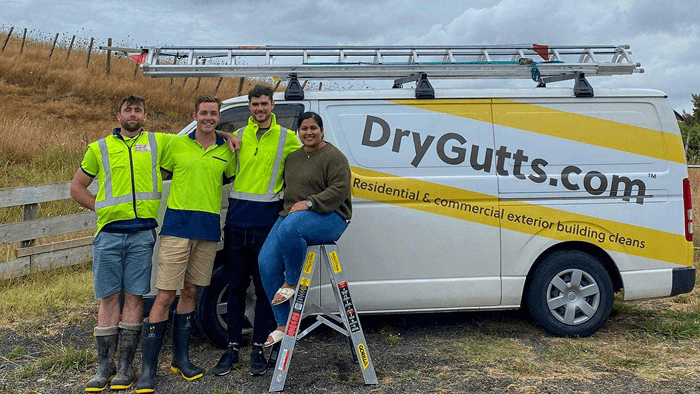 four drygutts employees standing beside company van smiling at the camera