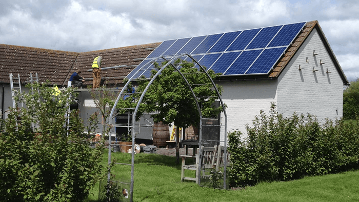 backyard of an English cottage surrounded by garden with solar panels on the tile roof