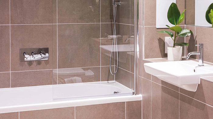 Customer stories_TJaiC Consultancy UK_tiled bathroom with focus on bathtub and white sink 