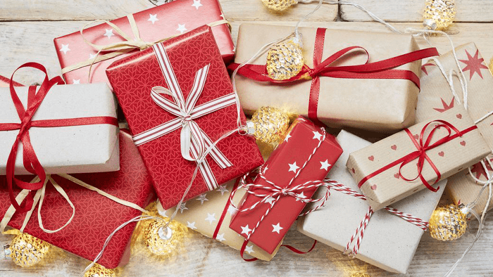 pile of Christmas gifts in red and brown paper wrapping 