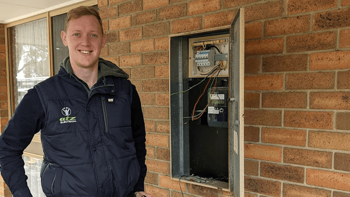 tradie standing outside a house next to switch board