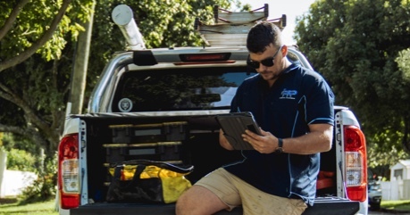 plumber sitting on the tray of a ute using Tradify