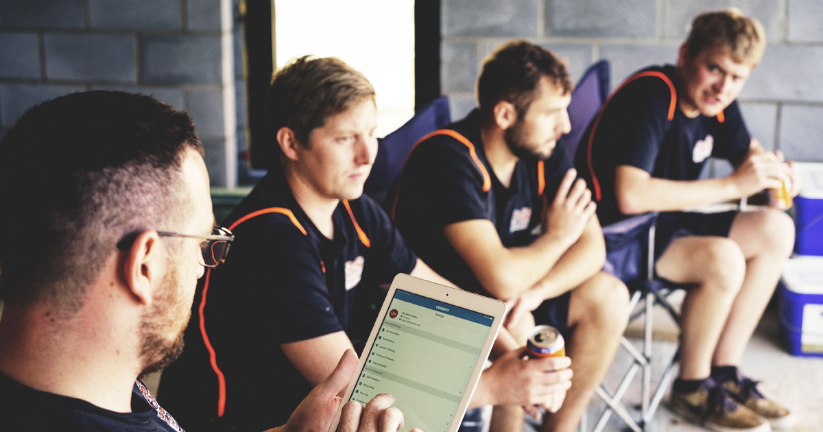 Four tradesmen sit and have a break. One works in Tradify from an ipad.