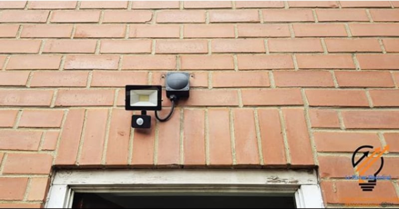 Close up photo of an outdoor sensor light on the exterior of a brown brick building
