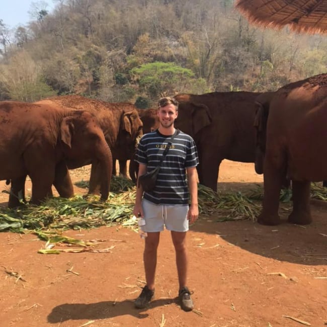 Ed on holiday in South-East asia, surrounded by baby elephants