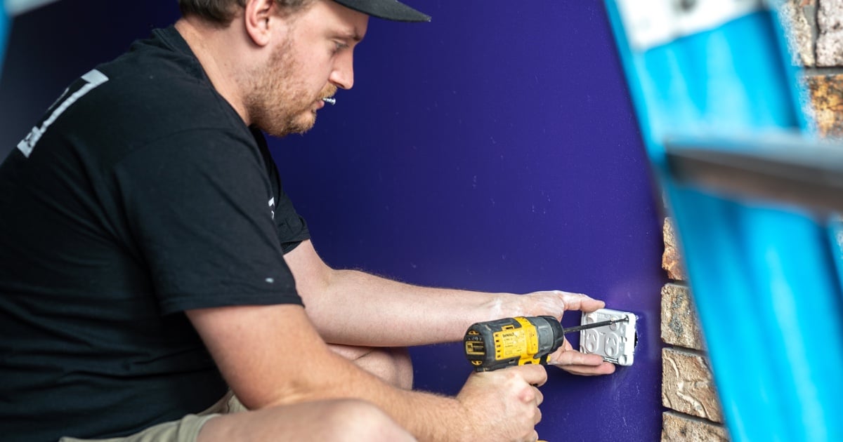 electrician installing a power socket with a DeWalt drill