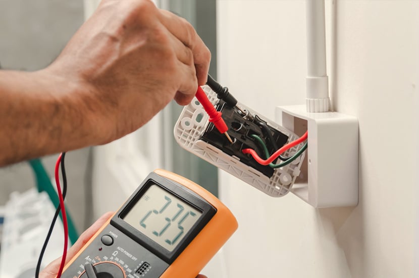 A photo of Freedom Electrical testing a power outlet. The meter reads 235.