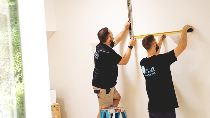 two tradies marking wall to install heating pump