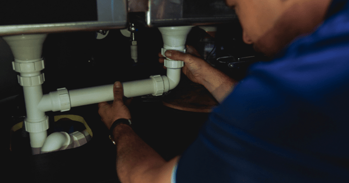 fitting a white pipe under the sink-min