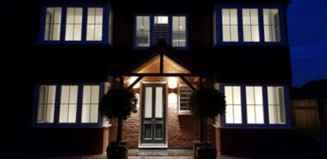 A photo of a brick house at night with brand new front porch lightning installed by Kennett Electrics