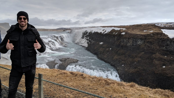sam in iceland next to a waterfall