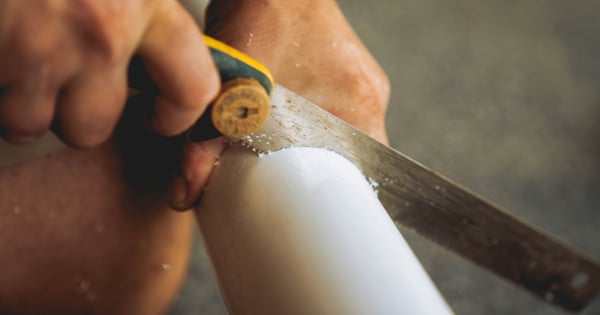 plumber cutting into pipe-min